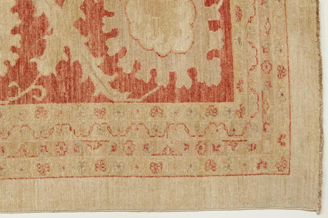 A large hand-knotted rug from Pakistan featuring a beige field and terracotta floral border.