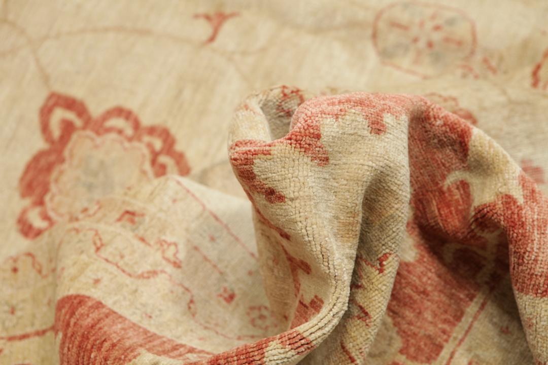 A large hand-knotted rug from Pakistan featuring a beige field and terracotta floral border.