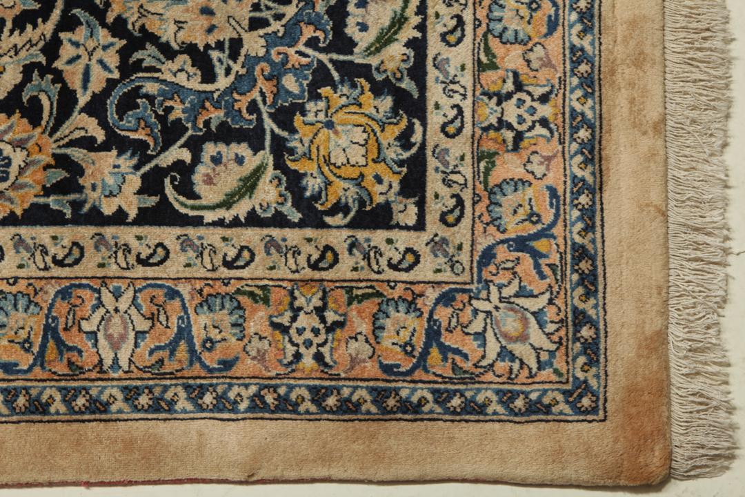 A large rectangular hand-knotted Mashad Astan Ghods rug with a beige field and floral motifs