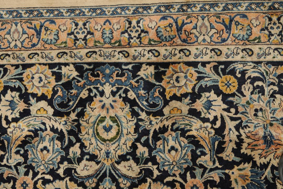 A large rectangular hand-knotted Mashad Astan Ghods rug with a beige field and floral motifs