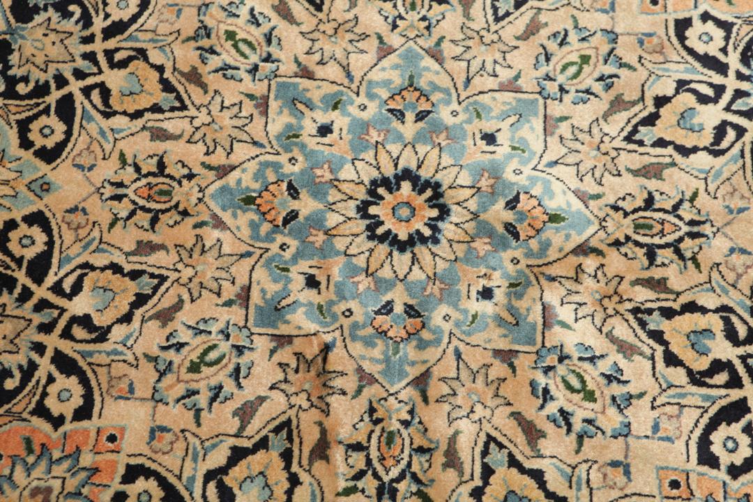A large rectangular hand-knotted Mashad Astan Ghods rug with a beige field and floral motifs