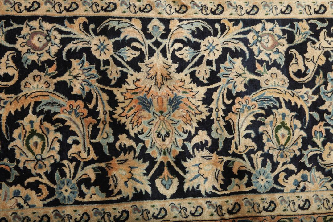 A large rectangular hand-knotted Mashad Astan Ghods rug with a beige field and floral motifs
