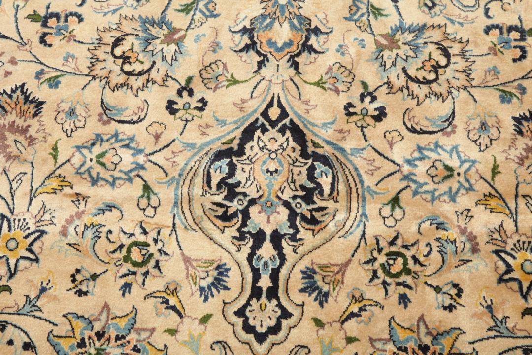 A large rectangular hand-knotted Mashad Astan Ghods rug with a beige field and floral motifs