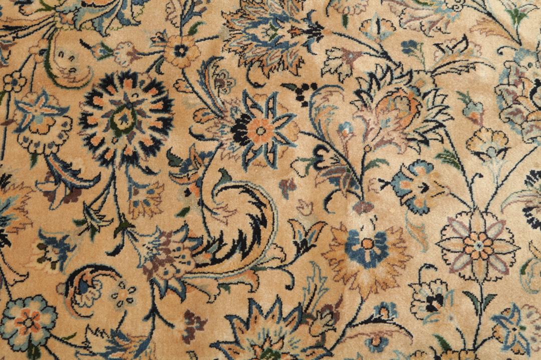 A large rectangular hand-knotted Mashad Astan Ghods rug with a beige field and floral motifs