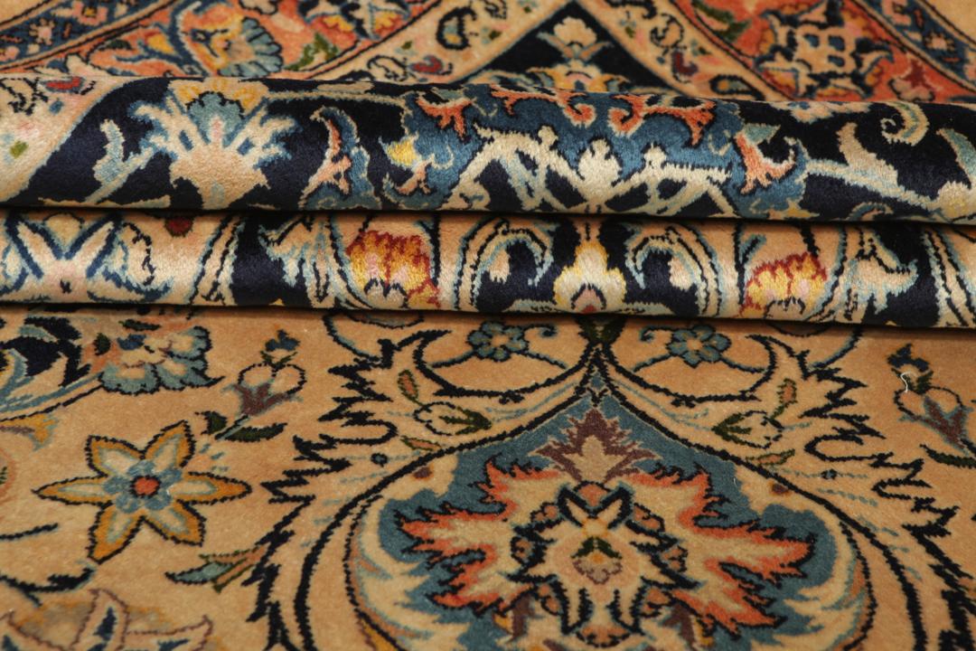 A large rectangular hand-knotted Mashad Astan Ghods rug with a beige field and floral motifs
