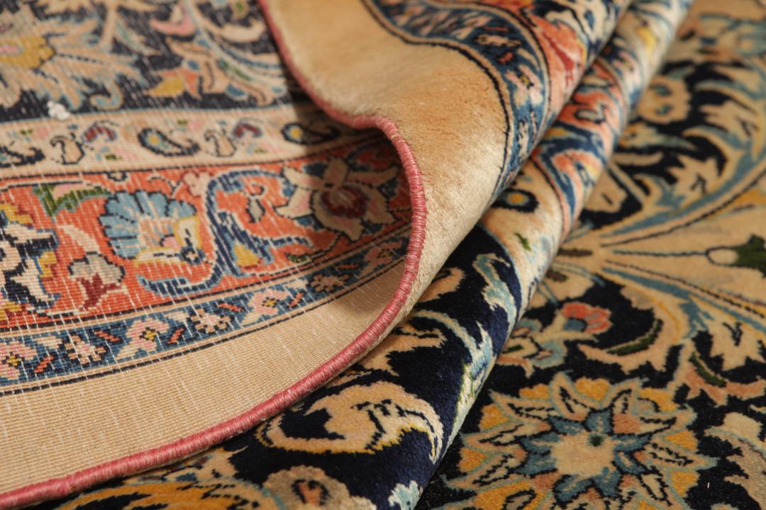A large rectangular hand-knotted Mashad Astan Ghods rug with a beige field and floral motifs