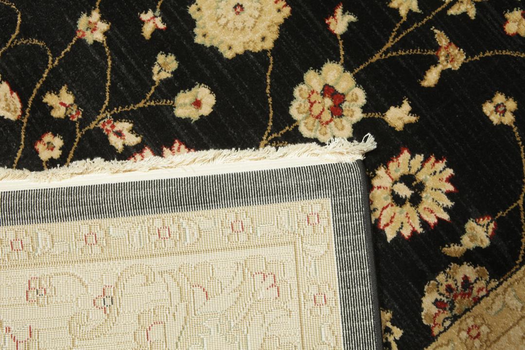 A rectangular floral rug with a black field and beige border.