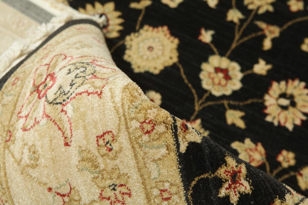 A rectangular floral rug with a black field and beige border.