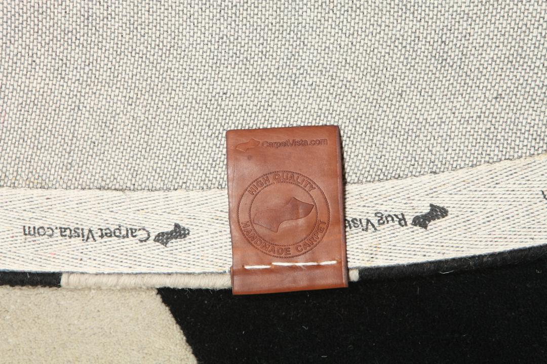 Een rond zwart en beige kleed met organische patronen