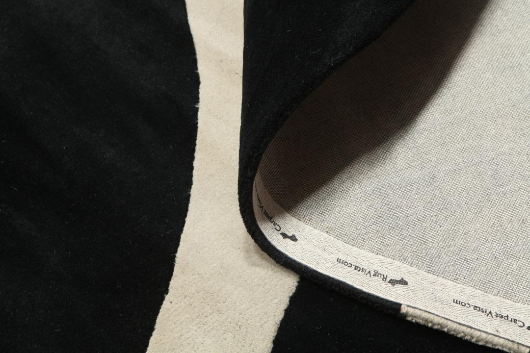 Een rond zwart en beige kleed met organische patronen