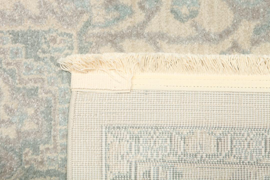 Cremefarvet og lyseblåt tæppe med et traditionelt mønstret design
