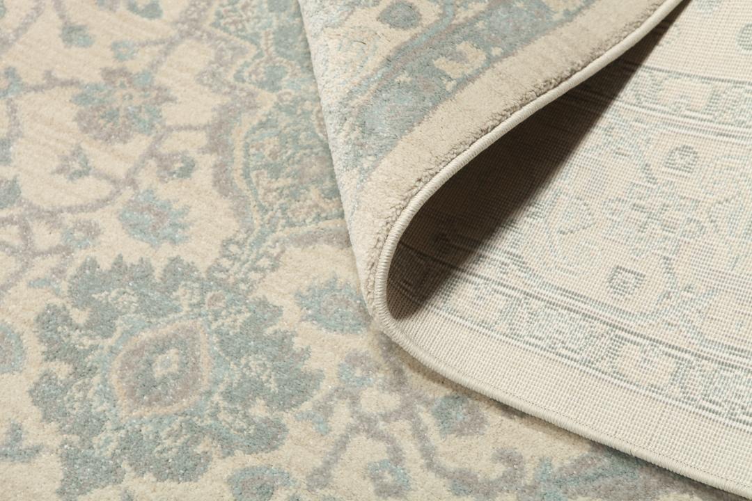 Cremefarvet og lyseblåt tæppe med et traditionelt mønstret design