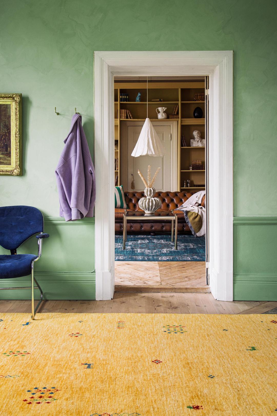 Een geel handgeknoopt wollen tapijt met kleine decoratieve tribale motieven.