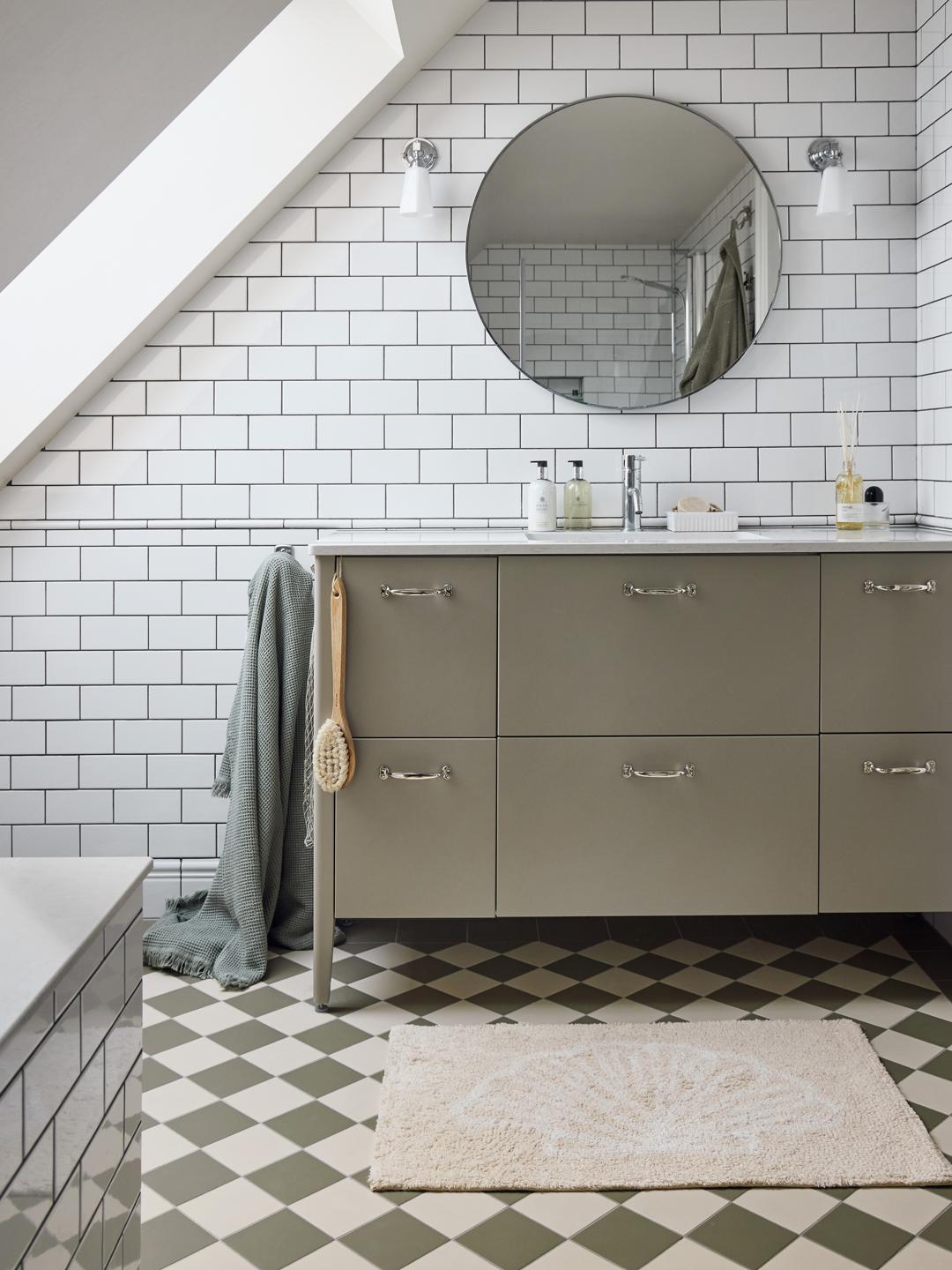 En beige bademåtte i bomuld med et hvidt muslingemønster.