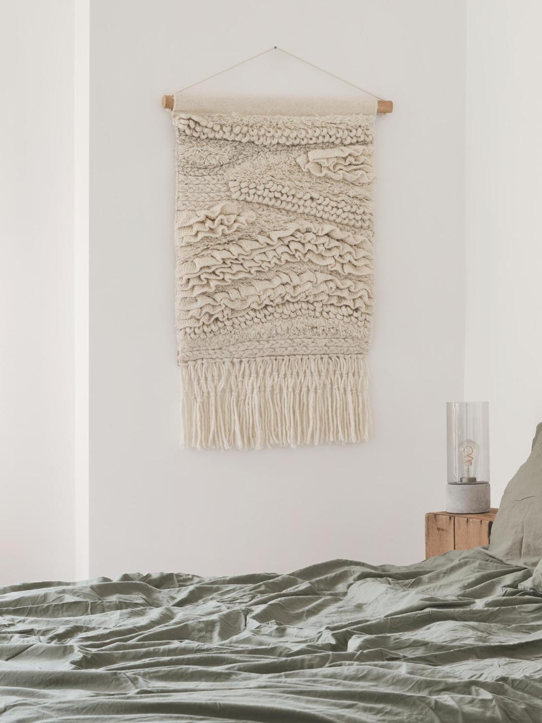 Een handgeweven witte en veelkleurige wanddecoratie met getextureerde lagen.