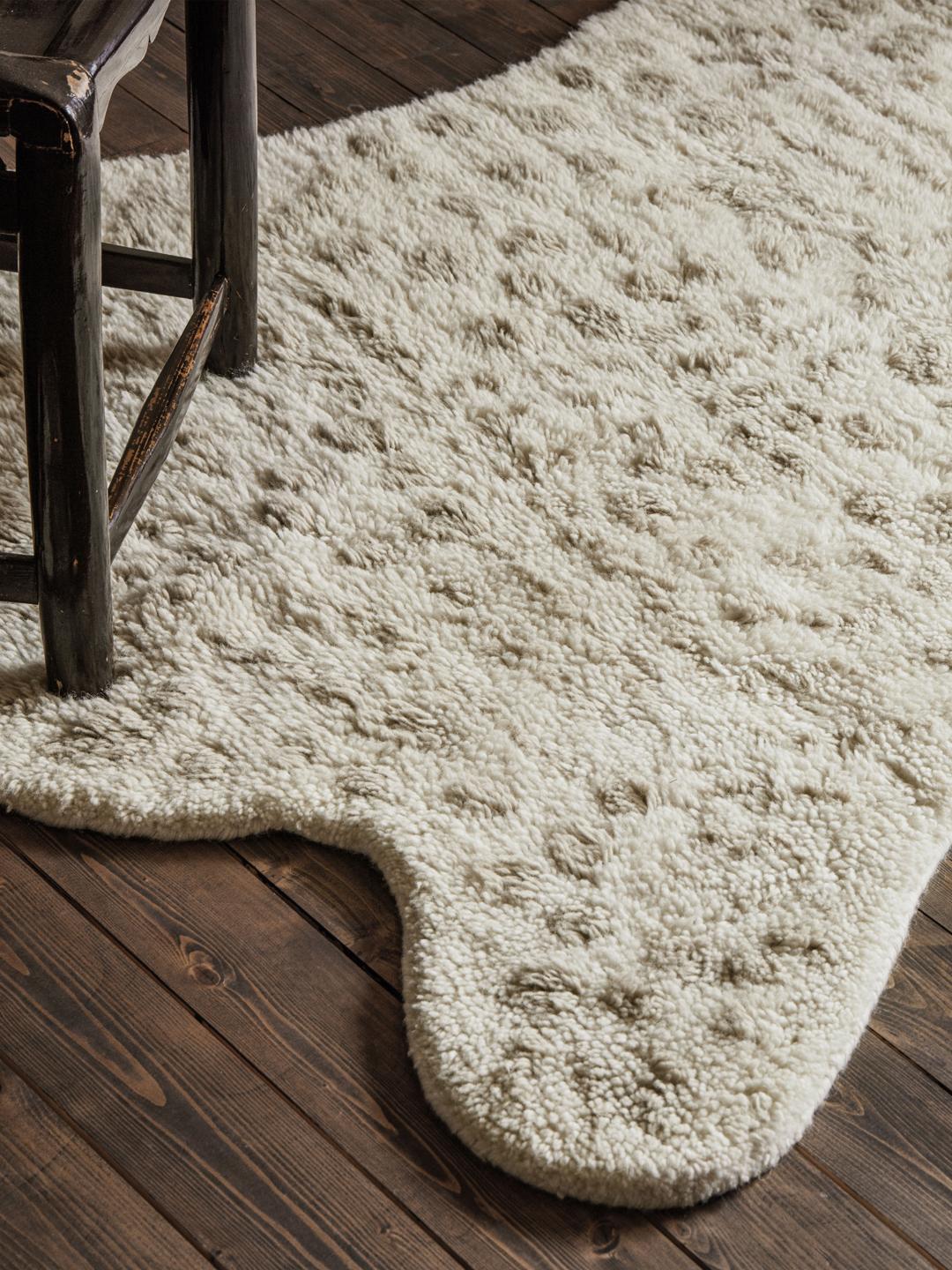 Onregelmatig gevormd wit en beige tapijt met een zachte pooltextuur