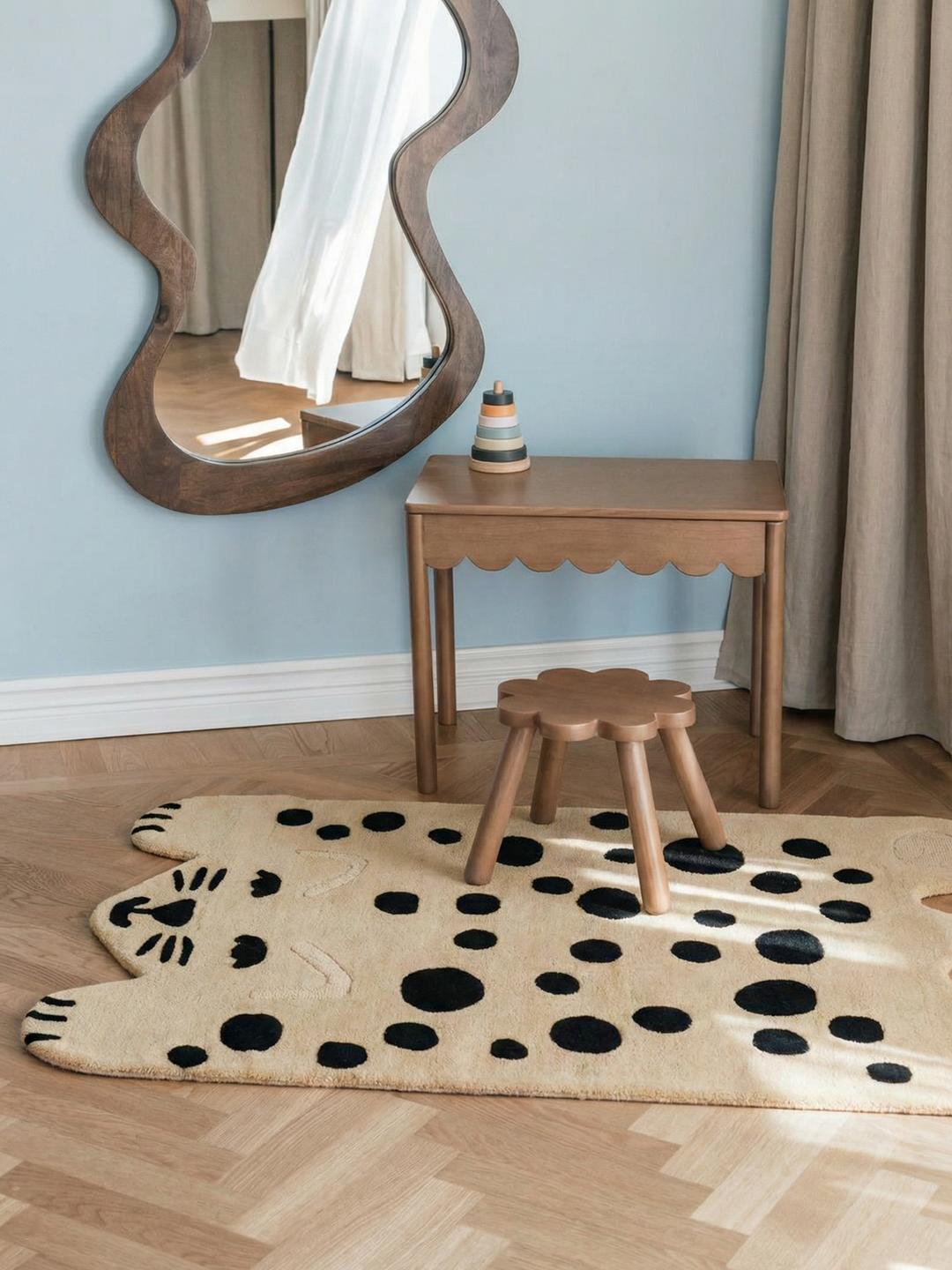 Een speels tapijt in de vorm van een kat in beige en donkergrijs met een zachte wollen pool