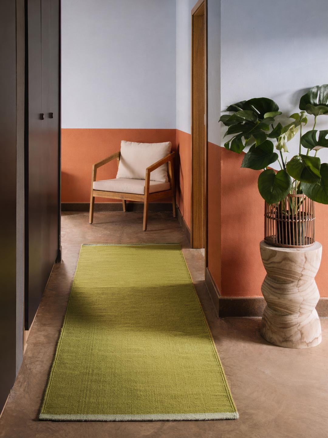 Een rechthoekige loper in een effen olijfgroene kleur met licht mintgroene randen.