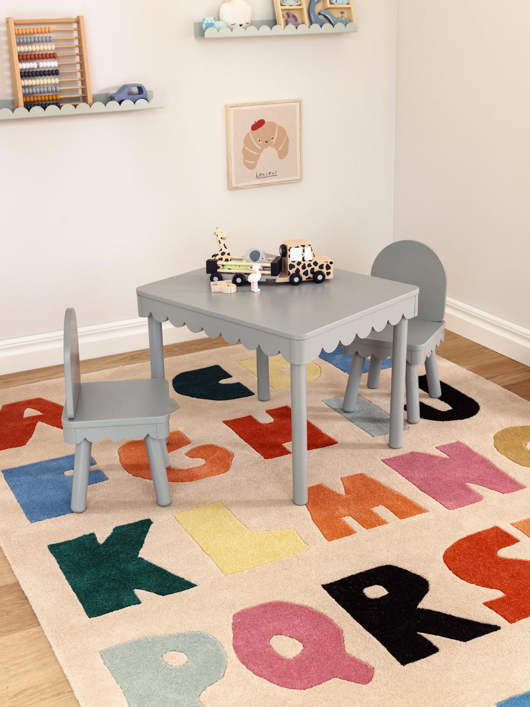 Een beige vloerkleed met een kleurrijk alfabetpatroon in verschillende tinten