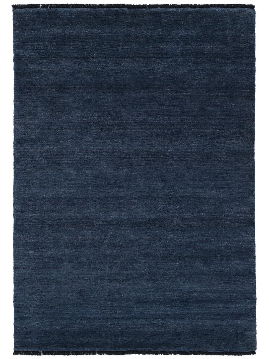 Een donkerblauw handgeweven vloerkleed met korte franjes langs de randen