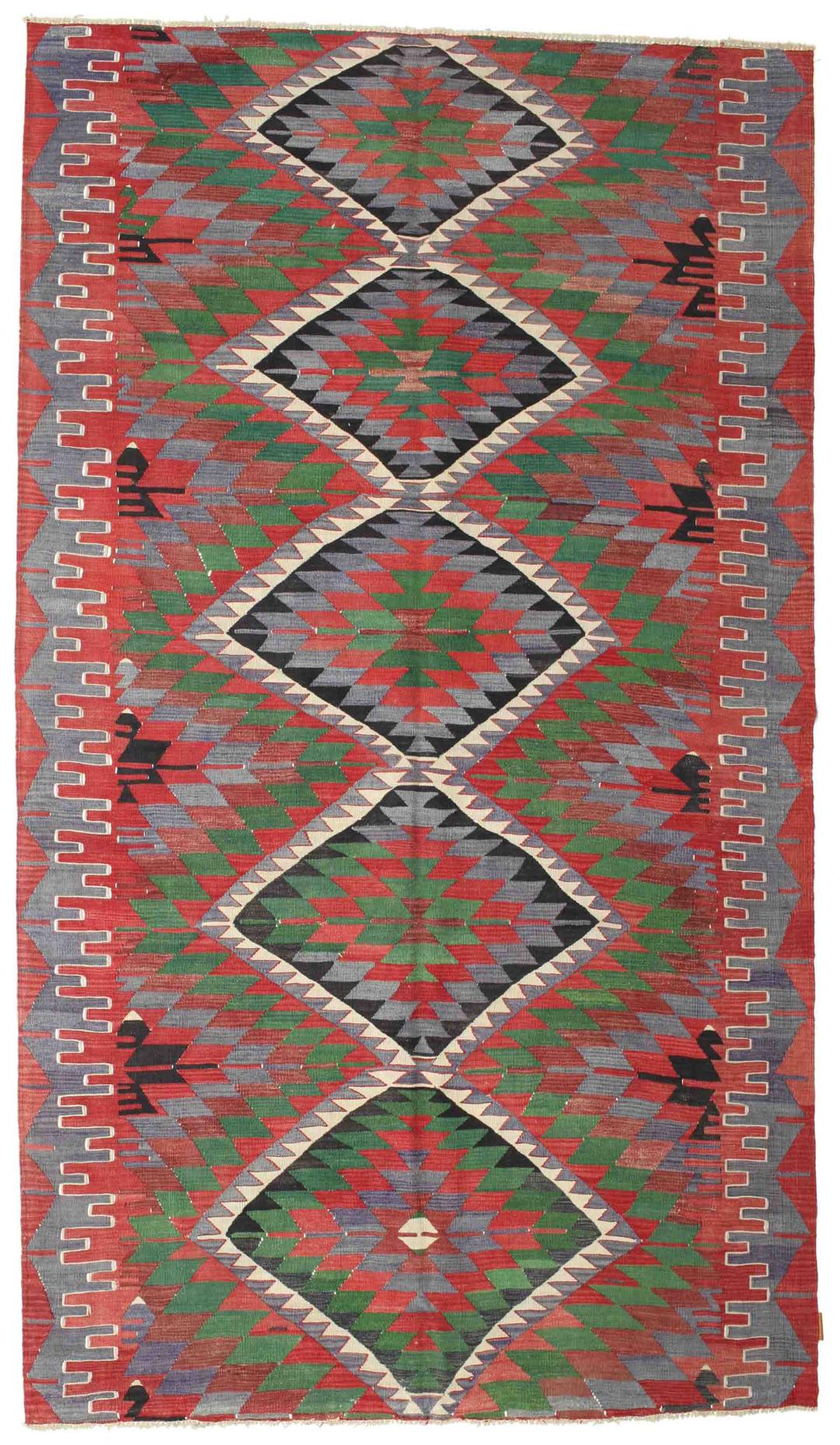 Un tapis Kelim turc vintage tissé à la main présentant un motif géométrique en losange aux couleurs vives rouge, vert et gris foncé.