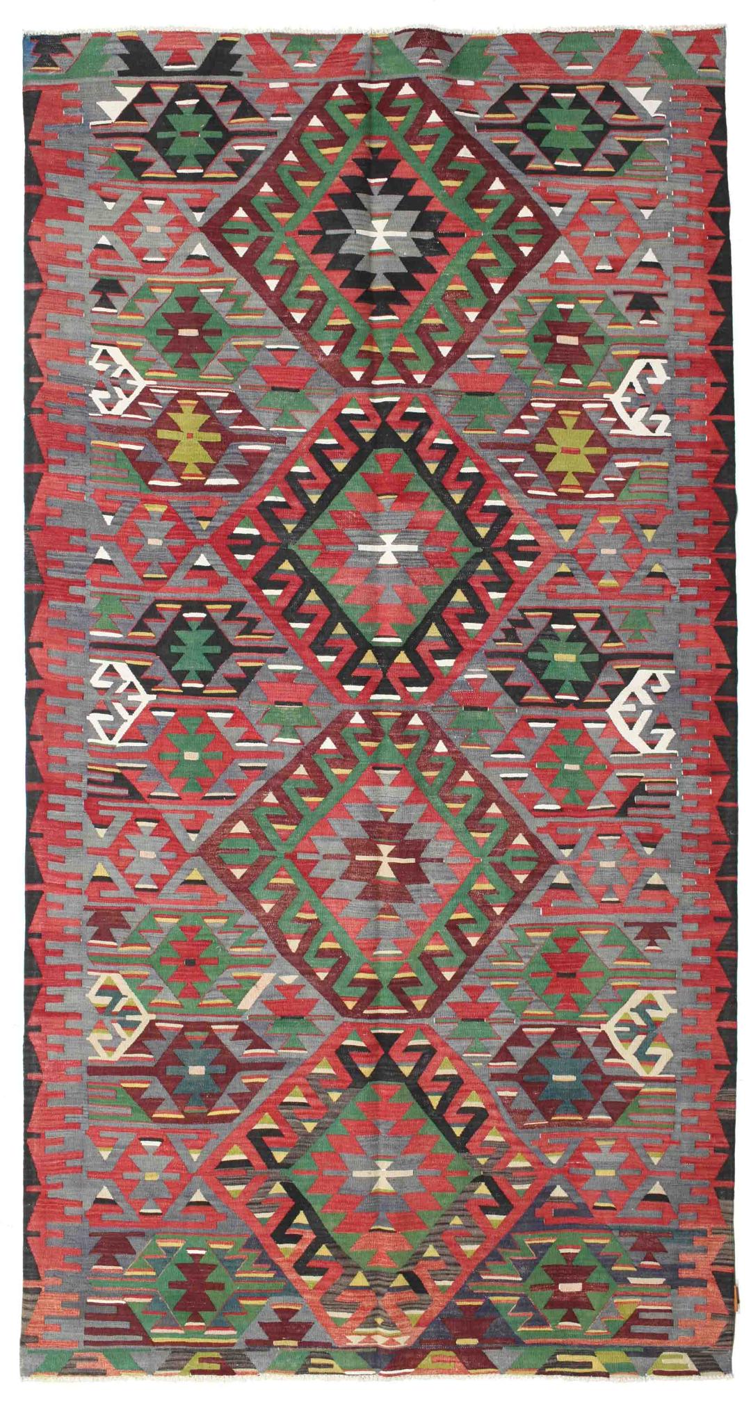 Tapis Kilim vintage tissé à la main originaire de Turquie avec des motifs géométriques colorés en rouge, vert et gris.