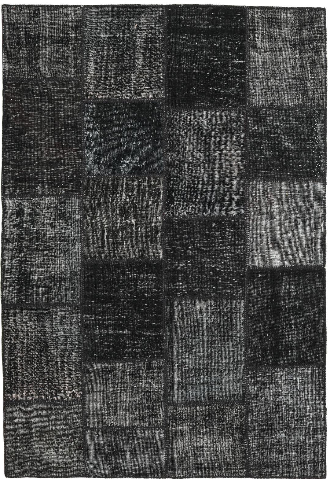 Een zwart patchwork vloerkleed handgemaakt in Turkije met gevarieerde texturen en tinten.