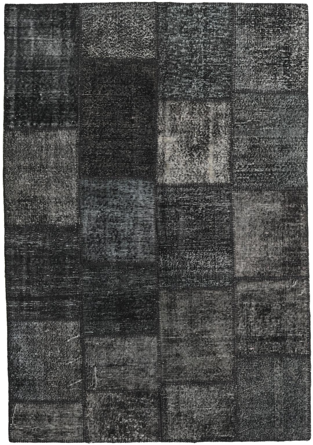 Een zwart patchwork vloerkleed met handgeknoopte wollen fragmenten in verschillende tinten uit Turkije.