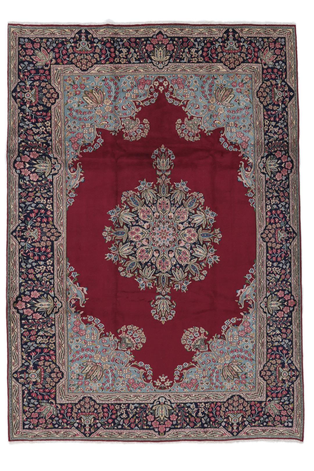 A hand-knotted Kerman rug with a red field and intricate floral medallion patterns.