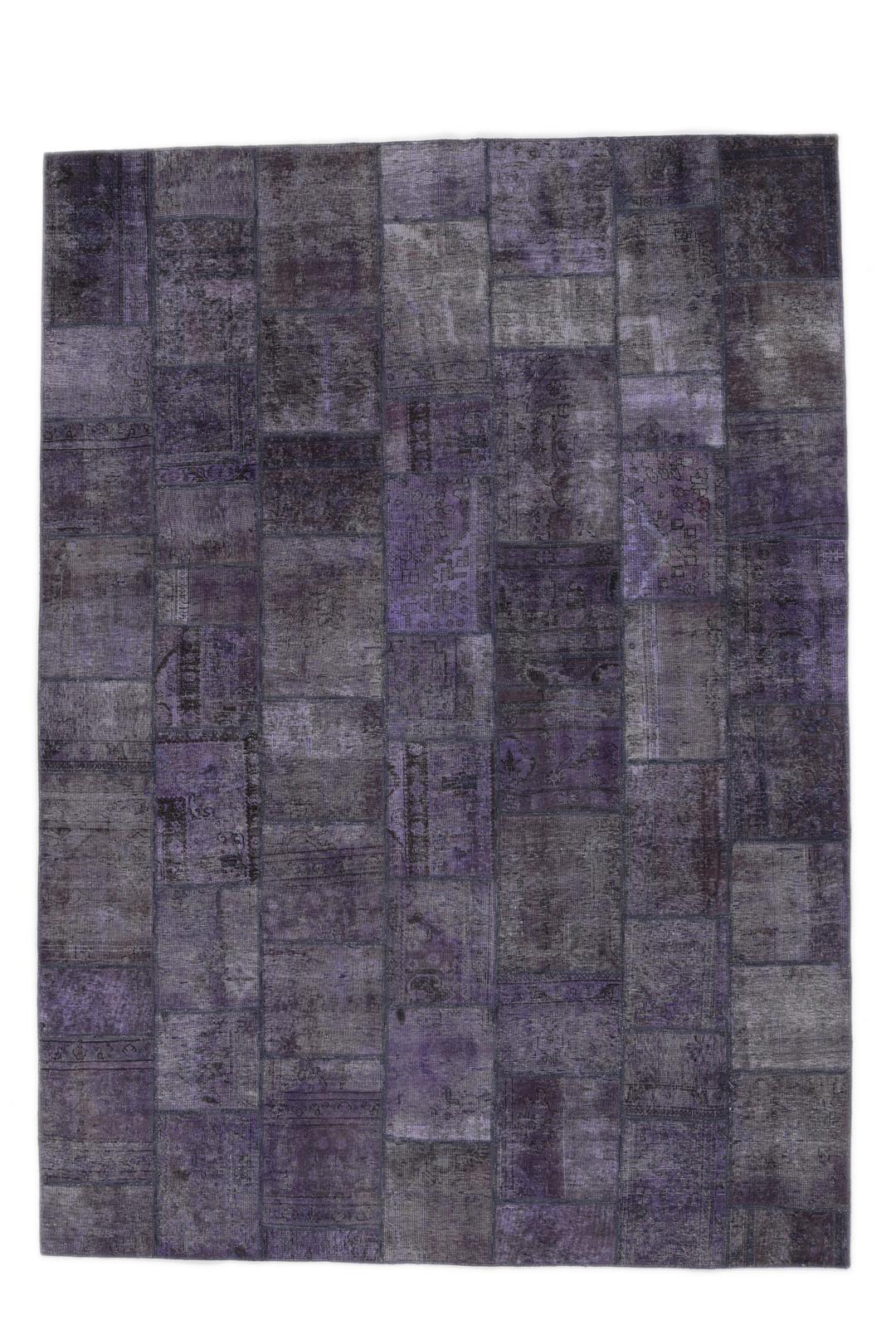 Een groot, handgeknoopt patchwork vloerkleed met ingewikkelde patronen in diepe donkerpaarse tinten.