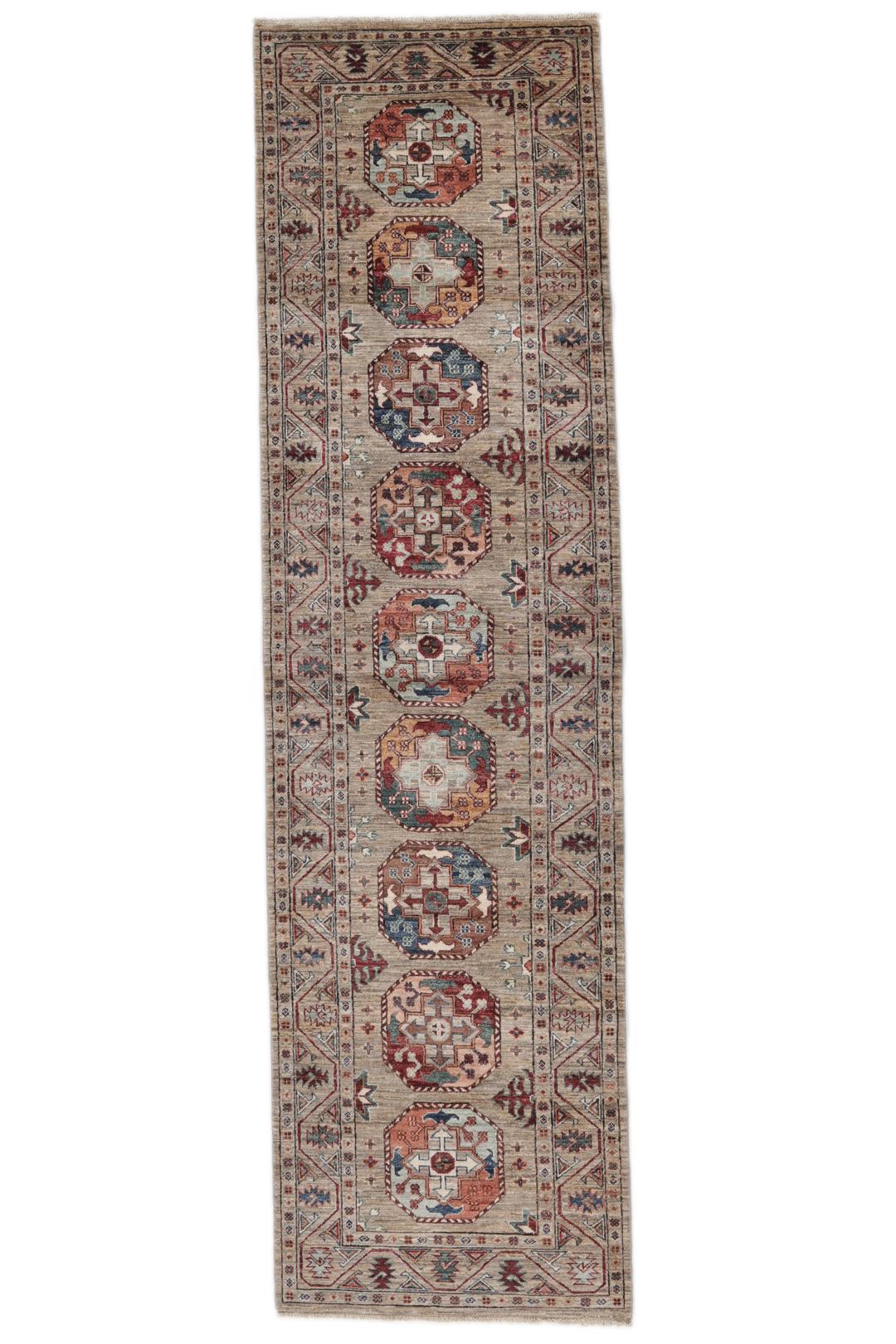Una alfombra pasillera afgana anudada a mano con tonos beige y motivos de medallones.