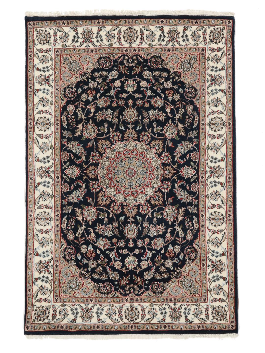 Un tapis rectangulaire Nain Indo présentant un champ bleu foncé avec un médaillon floral central et des bordures complexes, noué à la main en Inde.