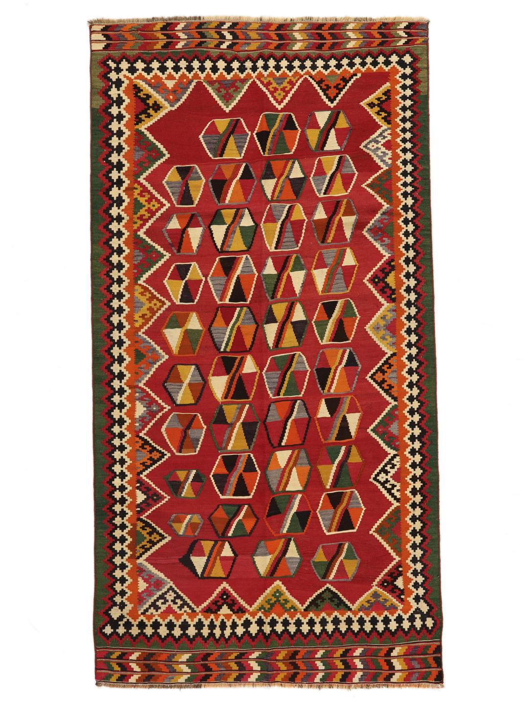 Et håndvævet vintage-kelimtæppe fra Mellemøsten med en rød flade og geometriske motiver.