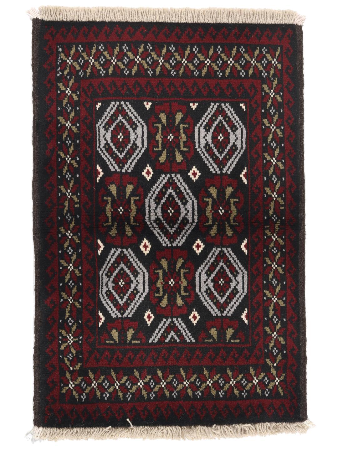A small, hand-knotted Beluch rug from the Middle East featuring geometric patterns in dark red and black.