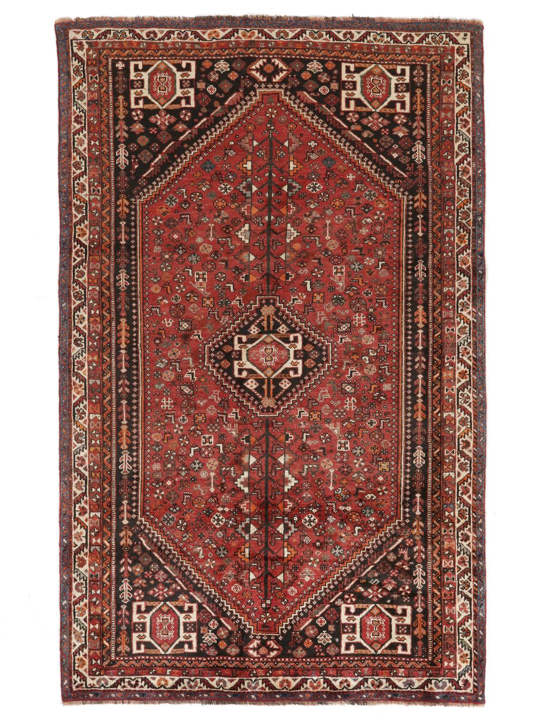 A hand-knotted Ghashghai rug from the Middle East in shades of red and black.