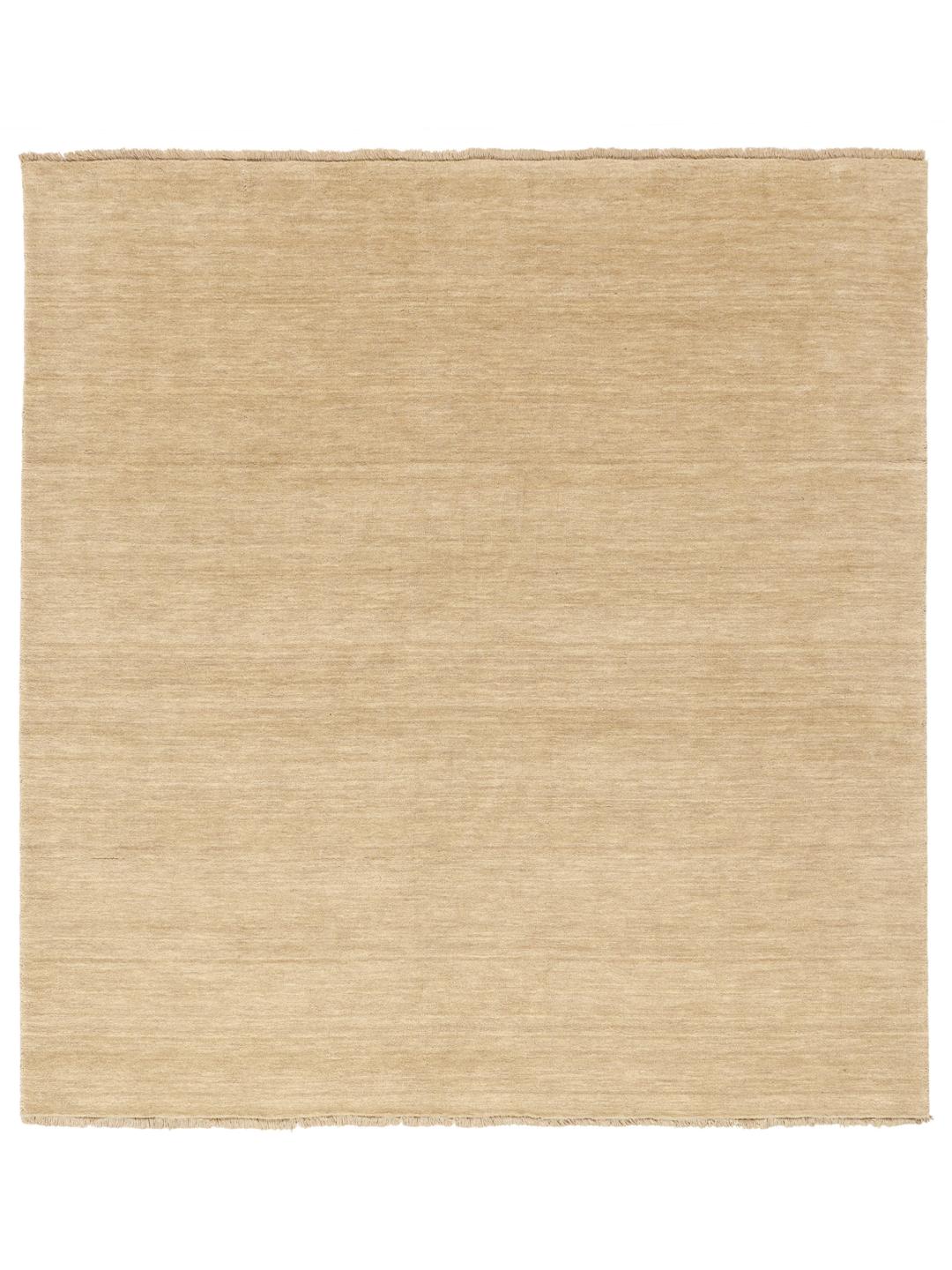 Een eenkleurig beige vloerkleed met verfijnde franjes