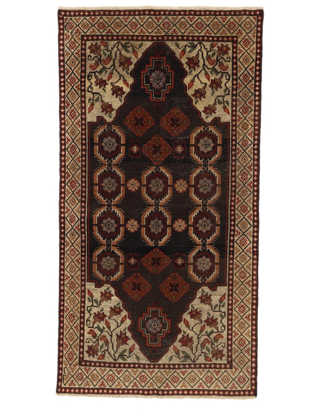 Een handgeknoopt tapijt uit het Midden-Oosten met een donker centraal medaillon en bloemrijke hoeken in tinten rood, beige en blauw.