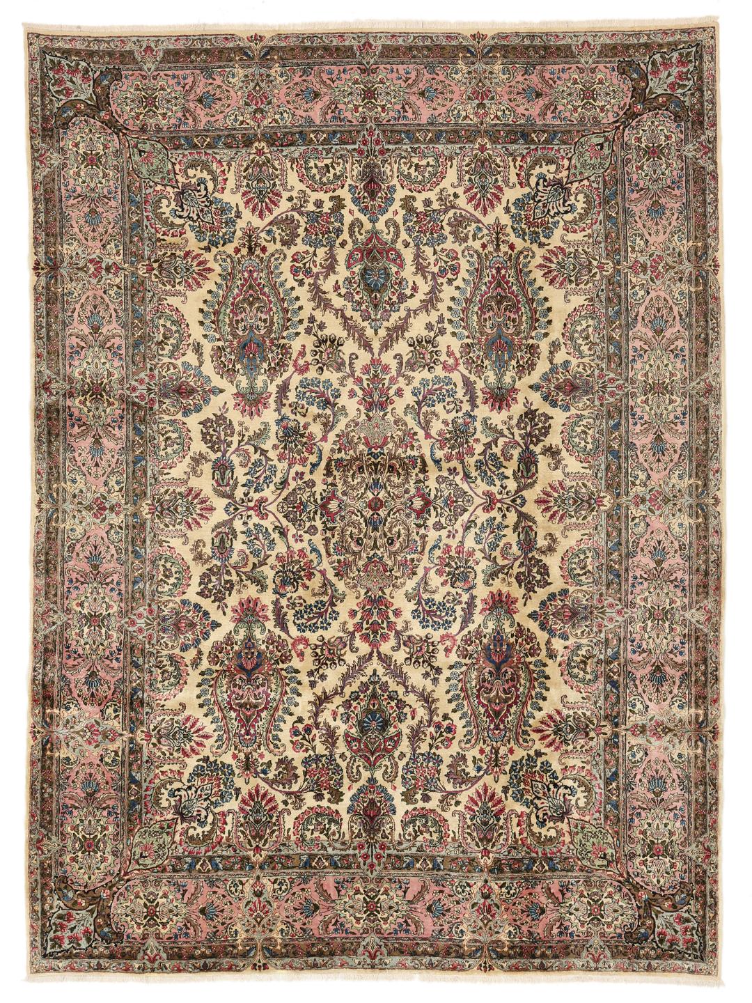 A large hand-knotted Middle Eastern Kerman rug with intricate floral patterns in beige and pink.