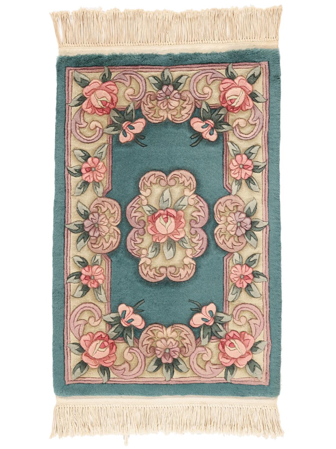 Et rektangulært uldtæppe fra Kina med en teal baggrund og lyserøde blomstermønstre.