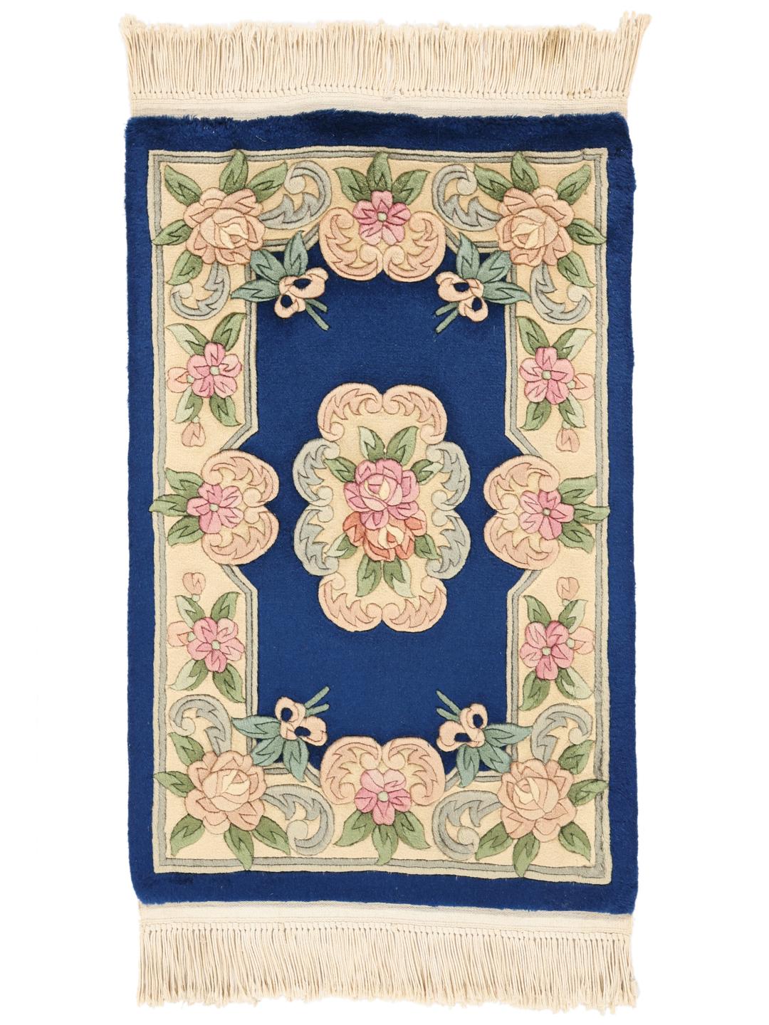 Een met de hand geknoopt tapijt uit China met een bloemenpatroon op een blauwe achtergrond.