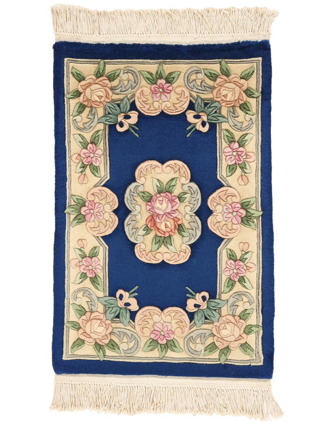 A hand-knotted floral rug from China with a deep blue field and pastel rose accents.