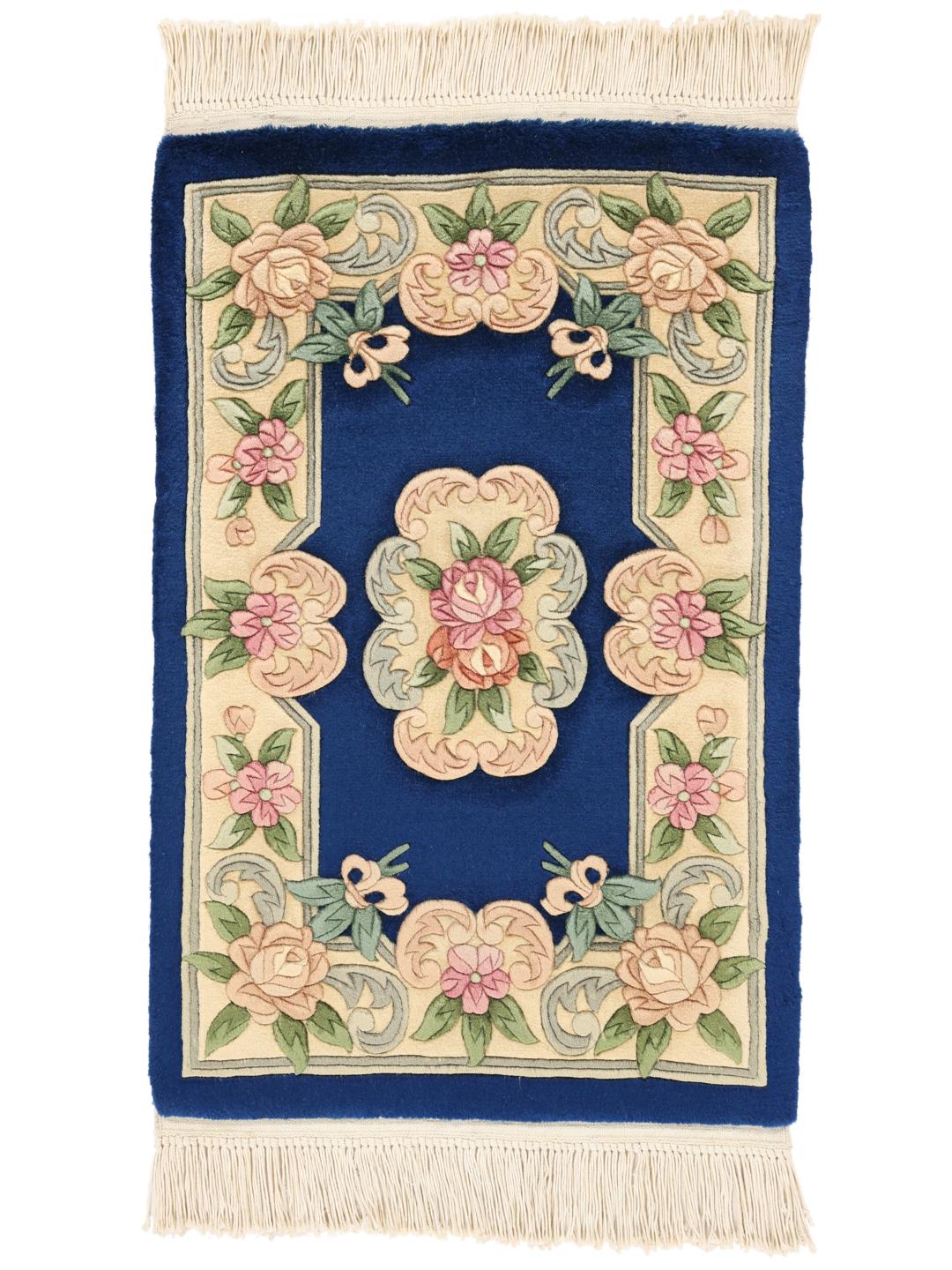 A rectangular hand-knotted rug from China featuring a deep blue field with floral motifs in shades of pink and beige.