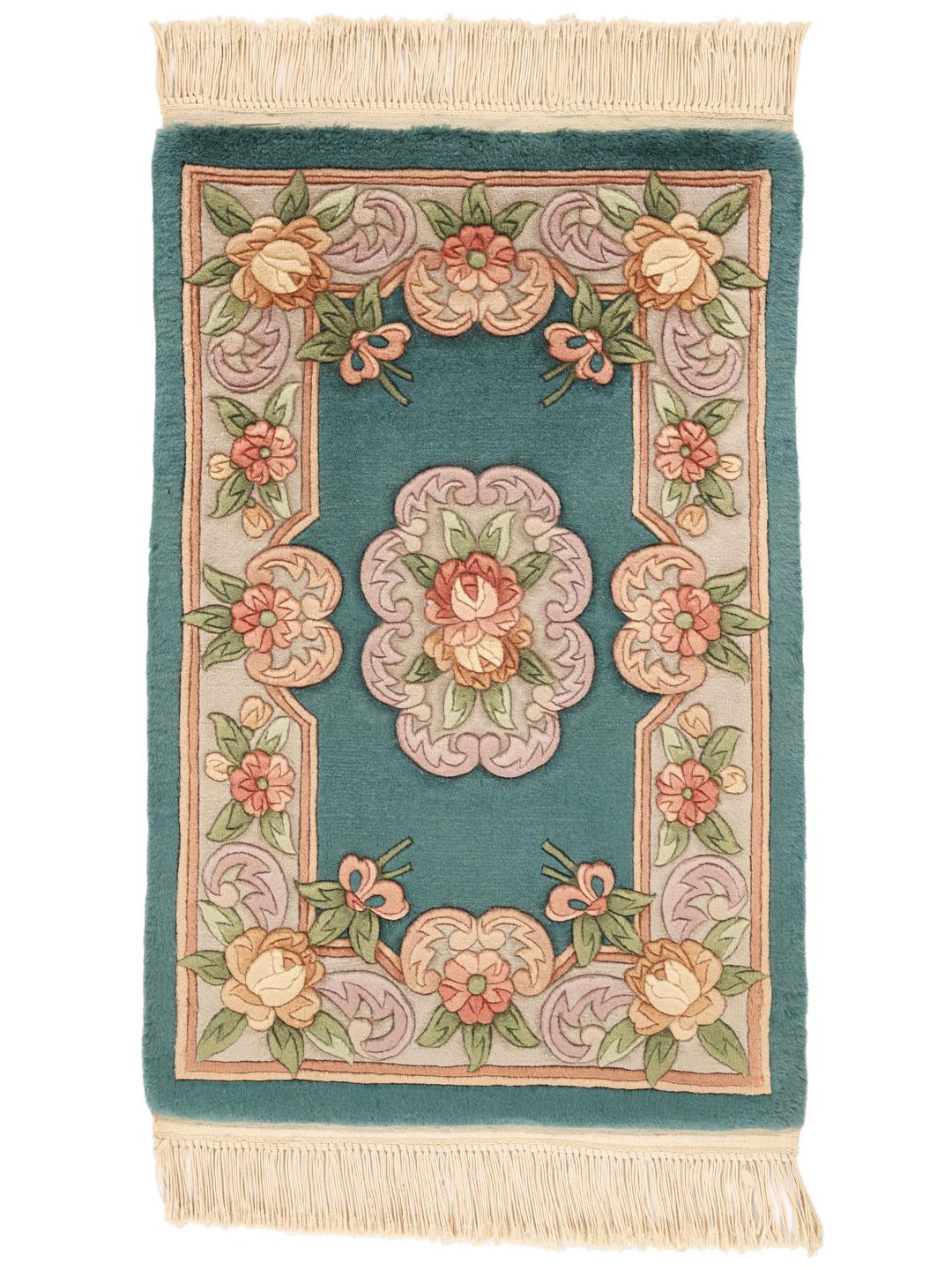 Et håndknyttet blomstret tæppe fra Kina med en petroleumsfarvet baggrund og blomstermotiver i pastelfarver.