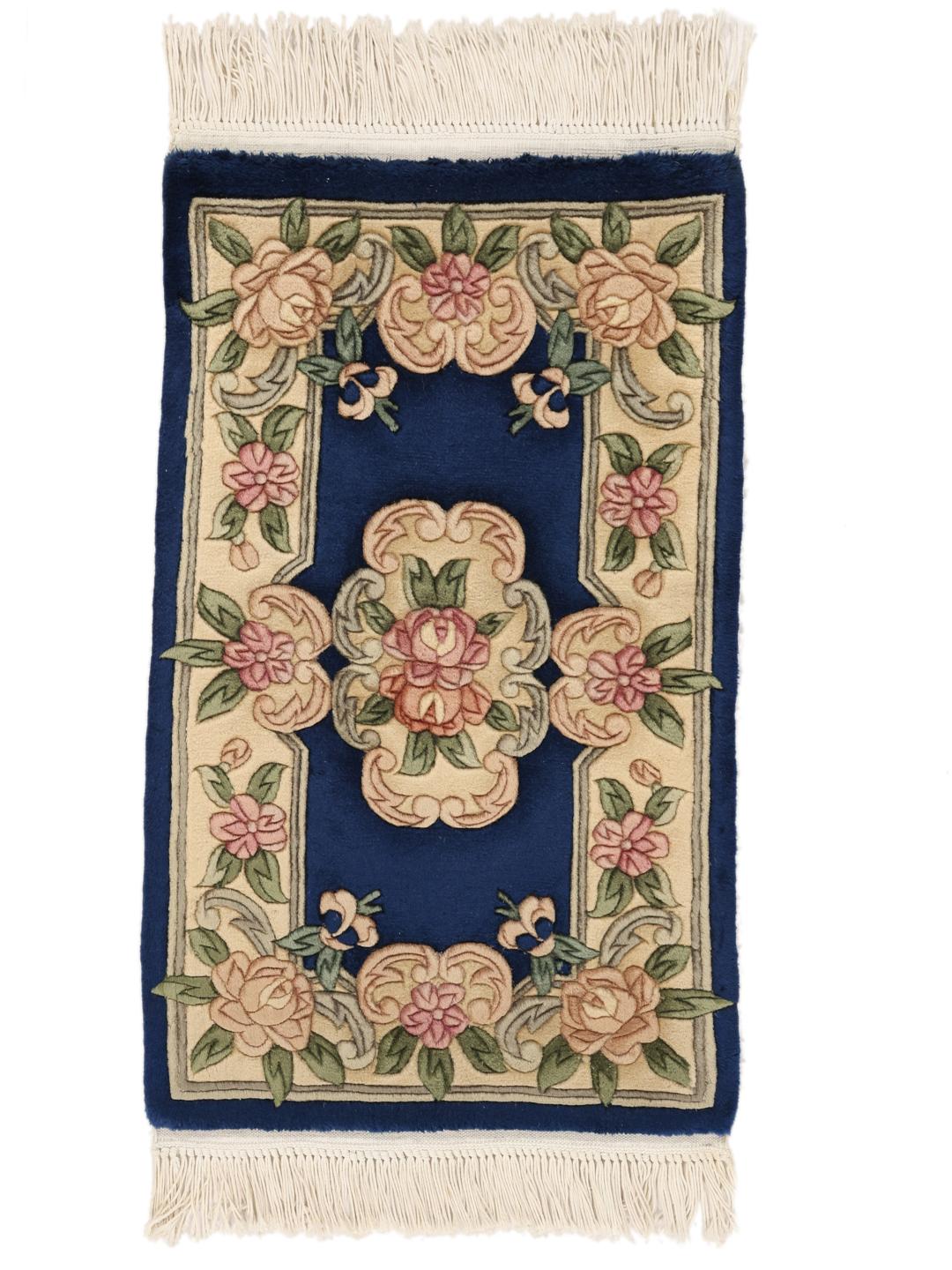 A rectangular, hand-knotted Chinese rug with a blue field and cream floral border.