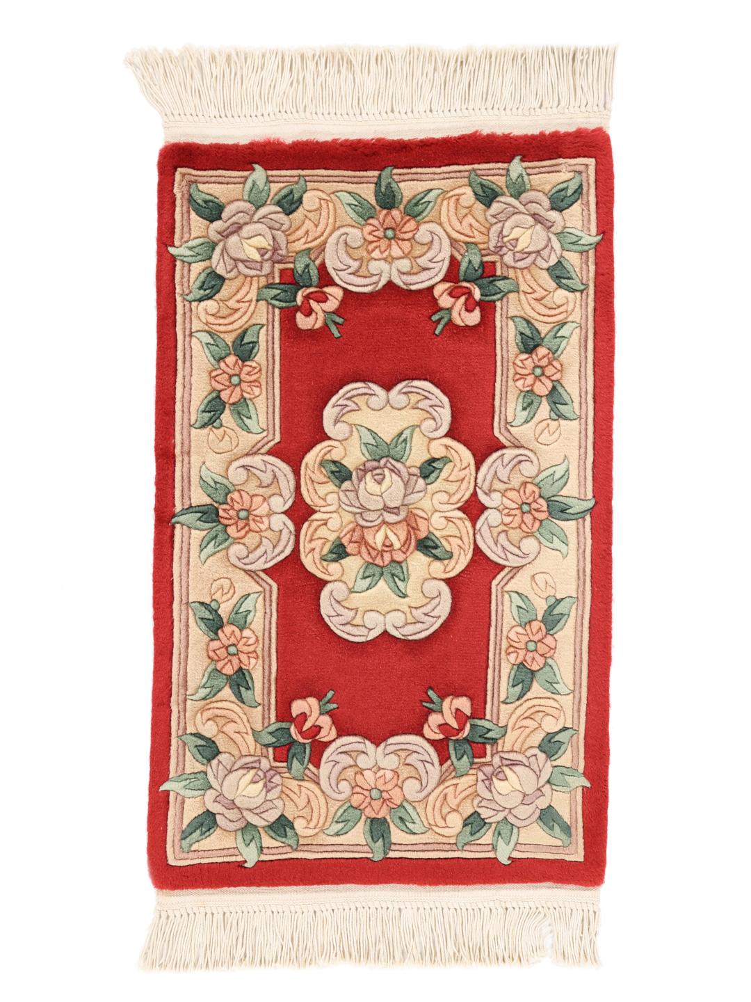 Un tapis chinois floral noué main dans des tons rouge et beige.