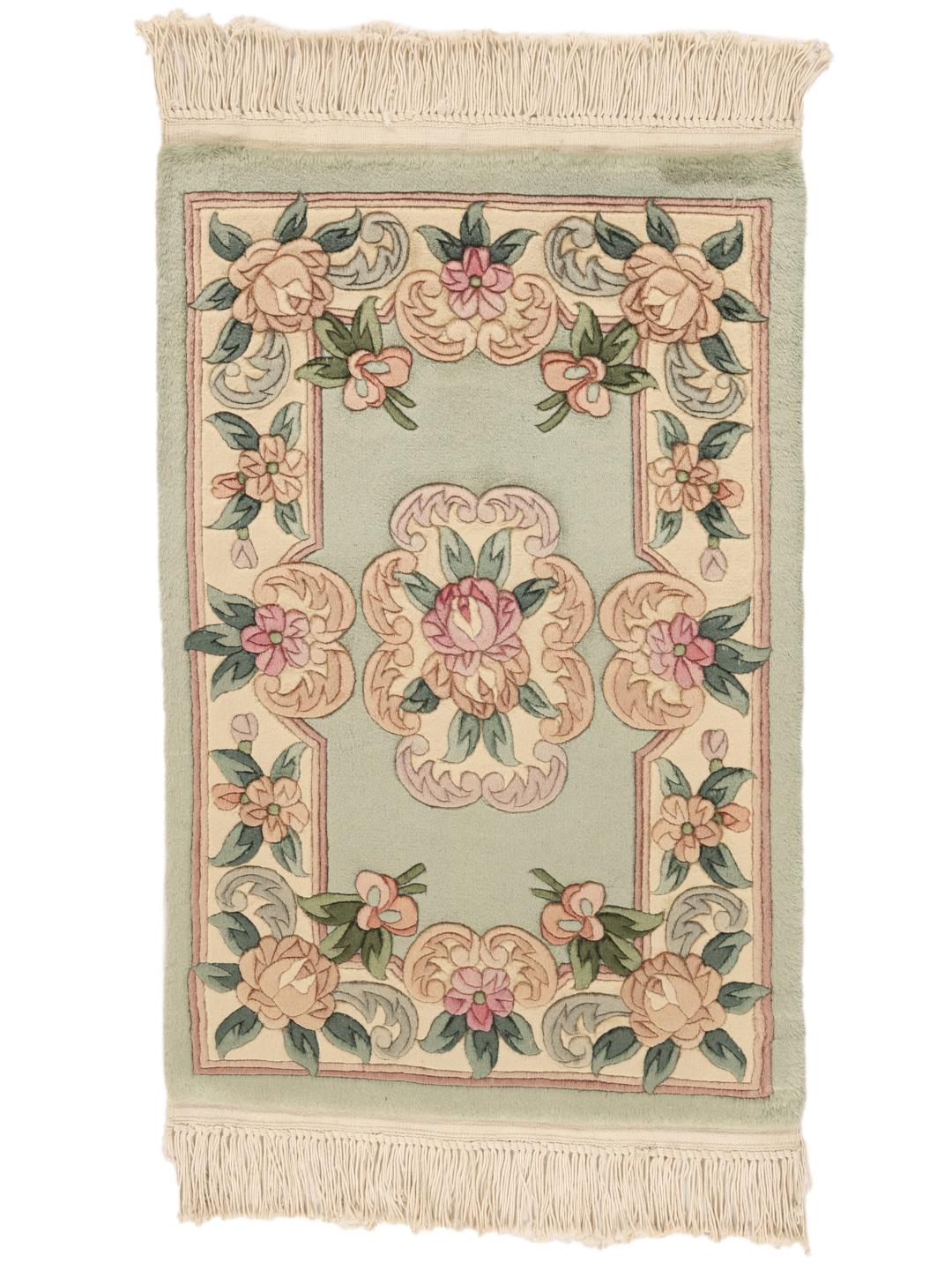 Et rektangulært håndlavet kinesisk tæppe med blomstermotiver i lysegrønne og sarte rosa nuancer.