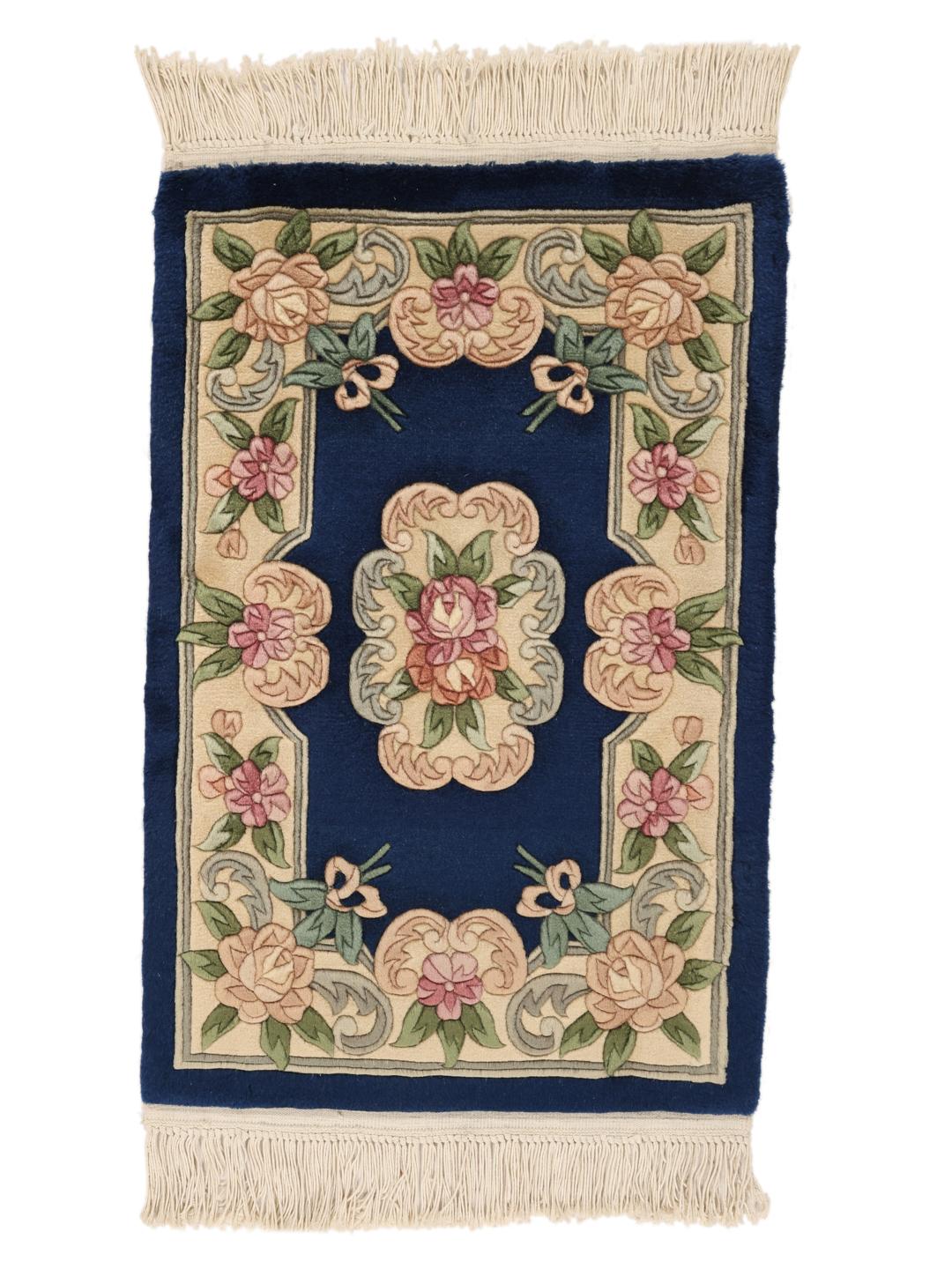 A hand-knotted Chinese rug with floral motifs on a deep blue background.