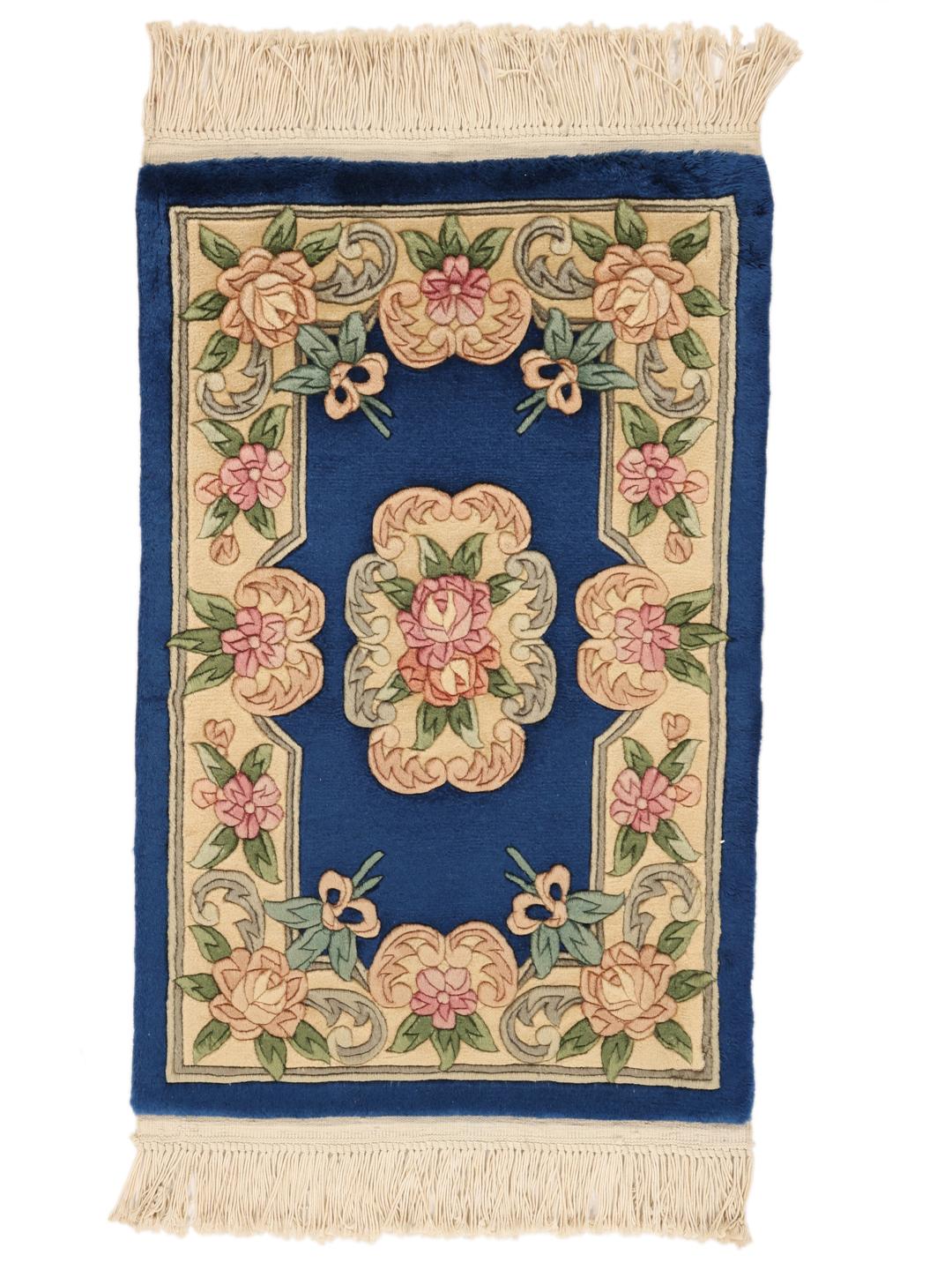 A rectangular hand-knotted Chinese rug with a floral pattern in blue and cream.