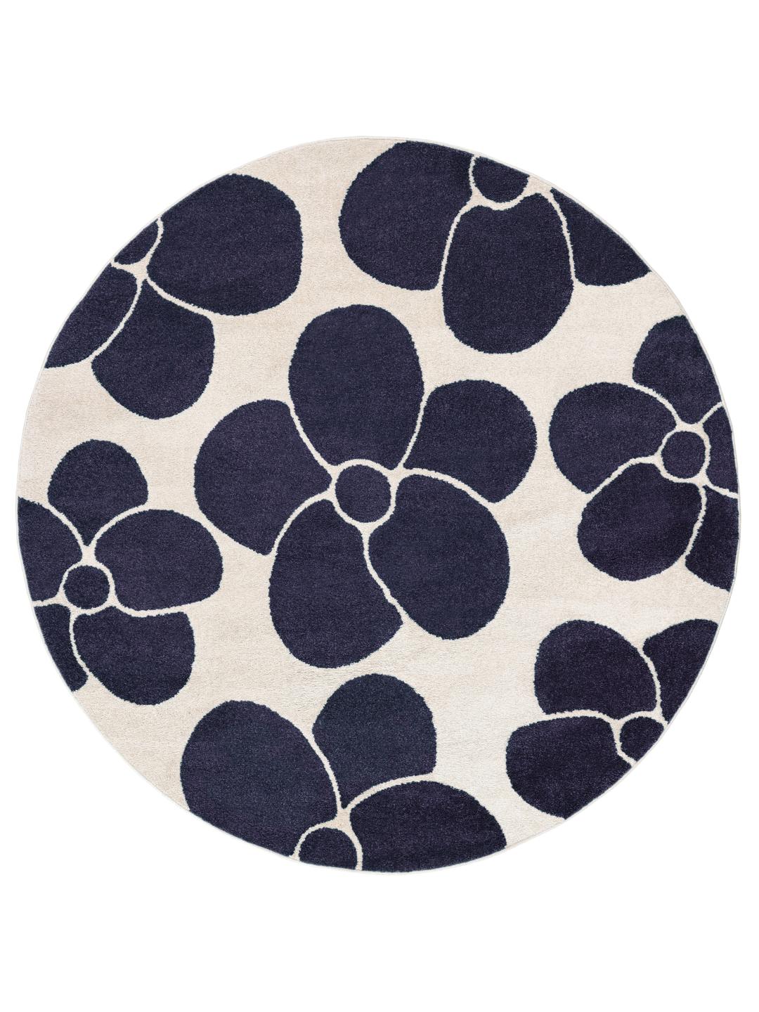 Un tapis rond avec un fond blanc cassé et de grands motifs de fleurs bleu foncé.