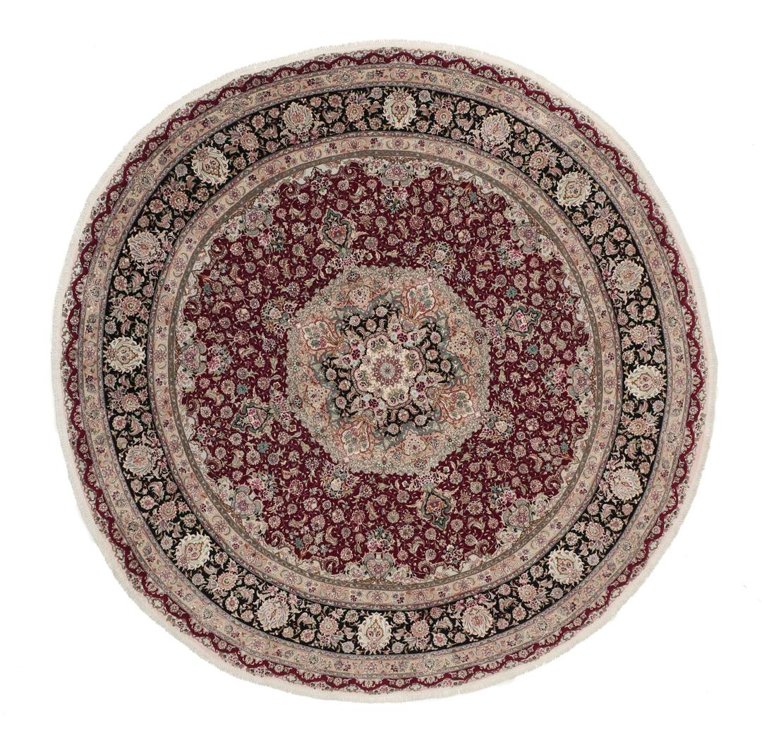 Een rond, handgeknoopt Tabriz-tapijt uit het Midden-Oosten met een levendig rood en zwart bloemendesign.